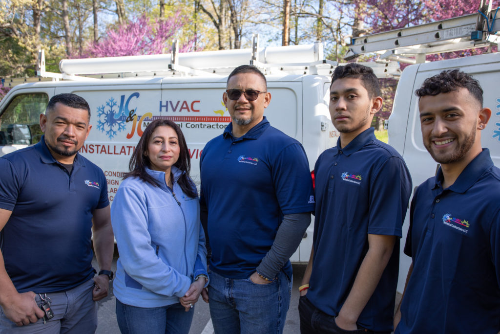 Five members of the JC & JC Mechanical Contractor team standing in front of their service trucks.