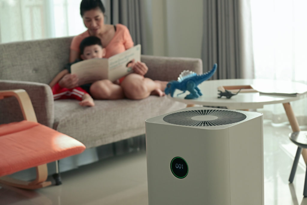 A mother reads a book to her son on the couch with a humidifier in front of them