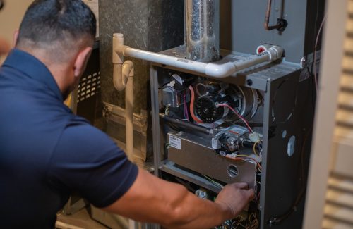 A man performing repairs on an opened heating system.