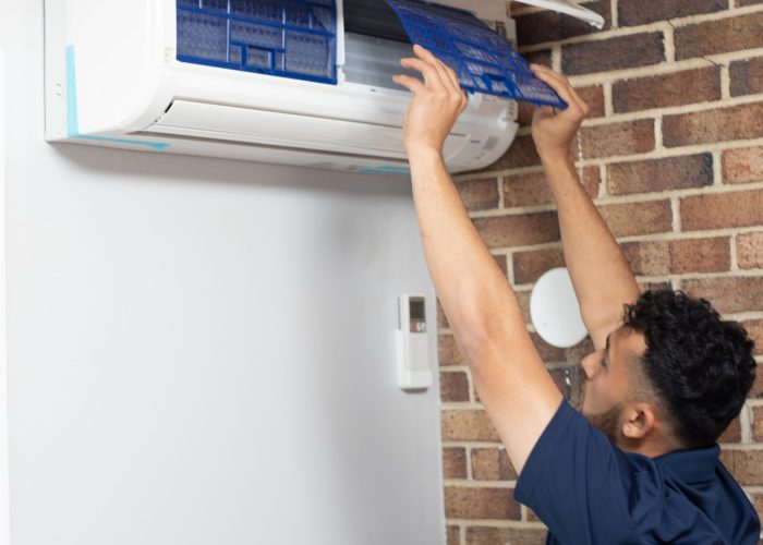 A man opening up a ceiling AC system to perform repairs.